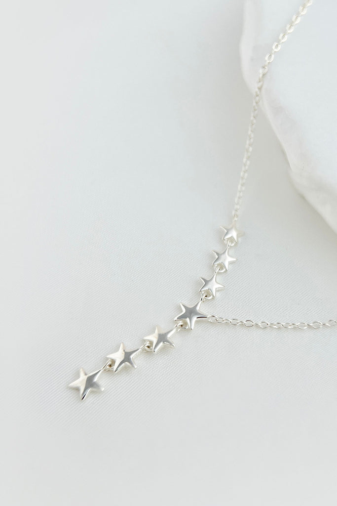 sterling silver chain necklace with a row of seven linked silver stars attached to the chain, the design is asymmetrical