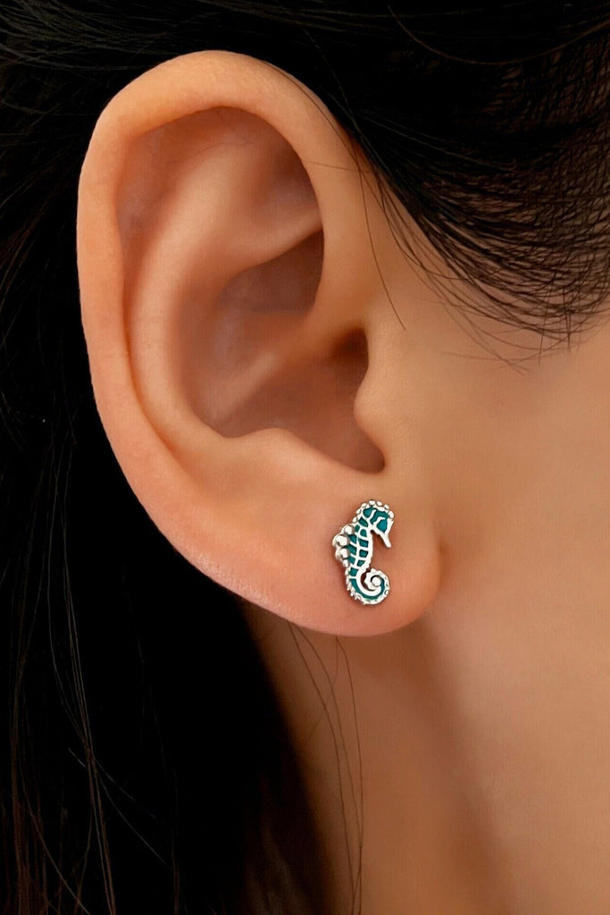 model wearing a silver and turquoise seahorse stud earring in the earlobe