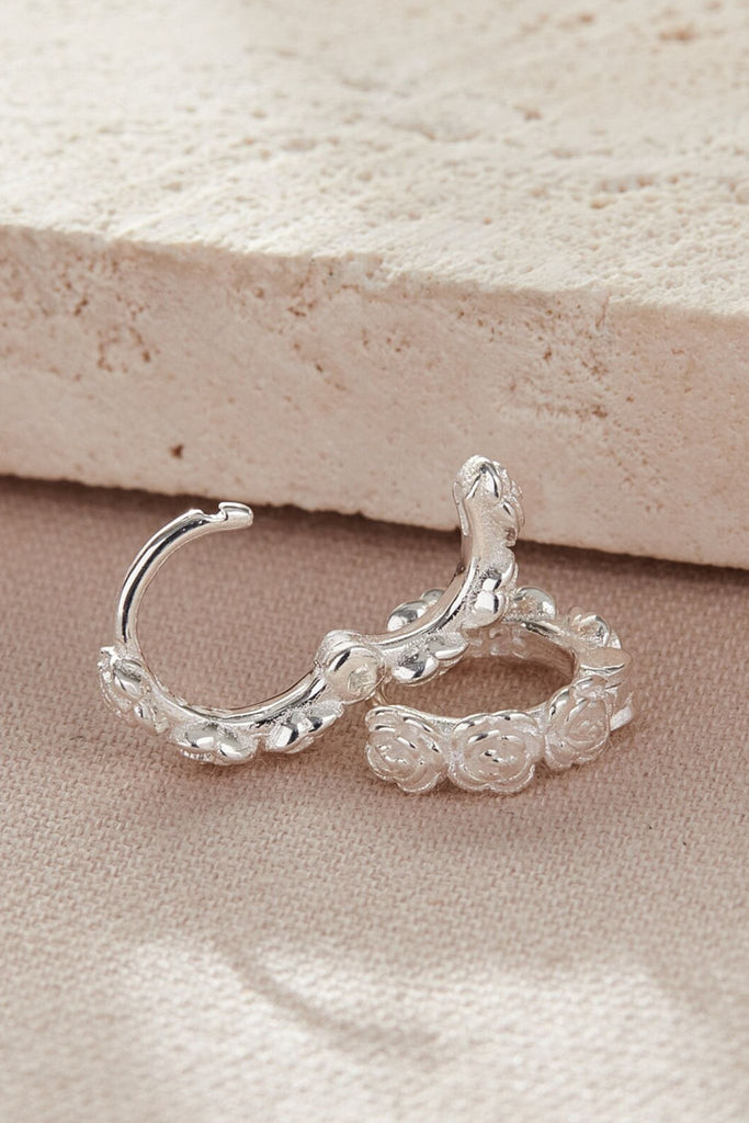 showing the latch back closure of these silver huggie hoops