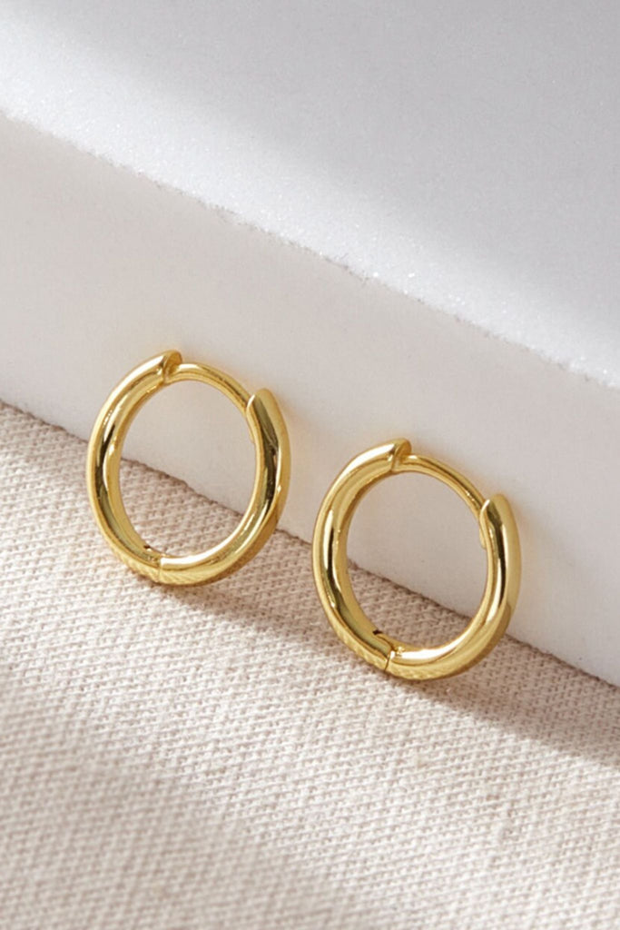 close up of the gold coloured minimalist huggie hoop earrings