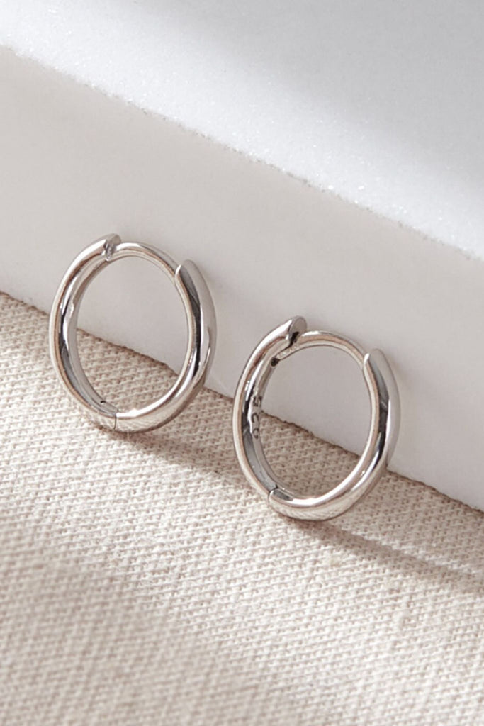 close up of the silver coloured minimalist huggie hoop earrings