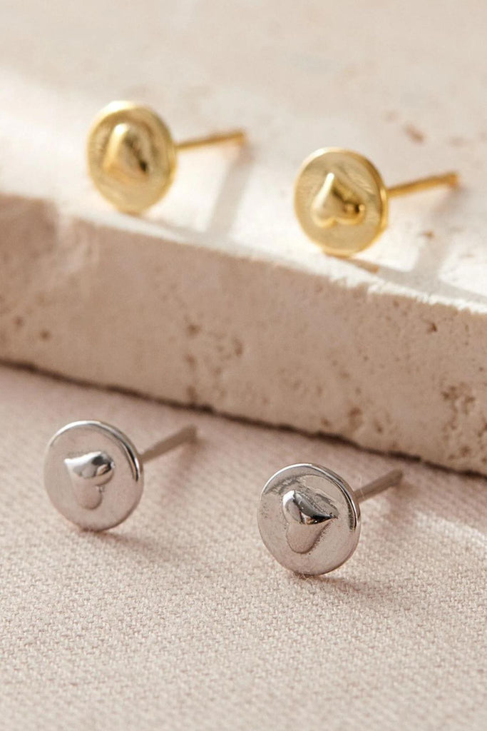 silver and gold round stud earrings with raised heart shapes in the middle