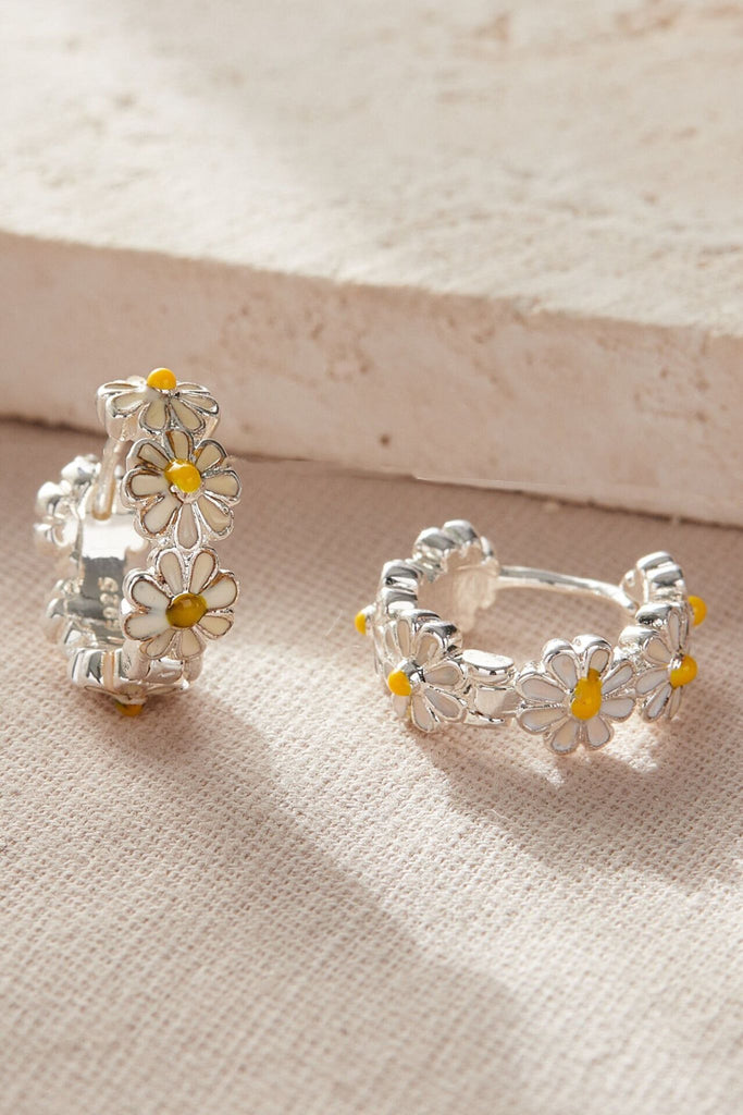 silver coloured huggie hoop earrings with white and yellow resin designed to look like a daisy chain