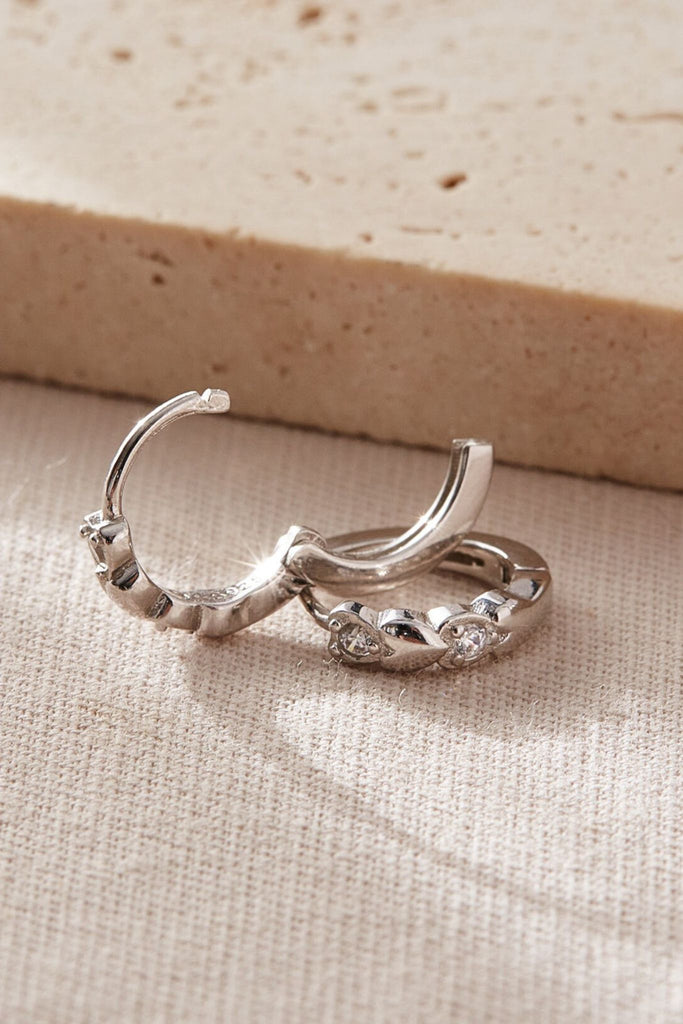 showing the latch closure fastening of the silver heart hoops