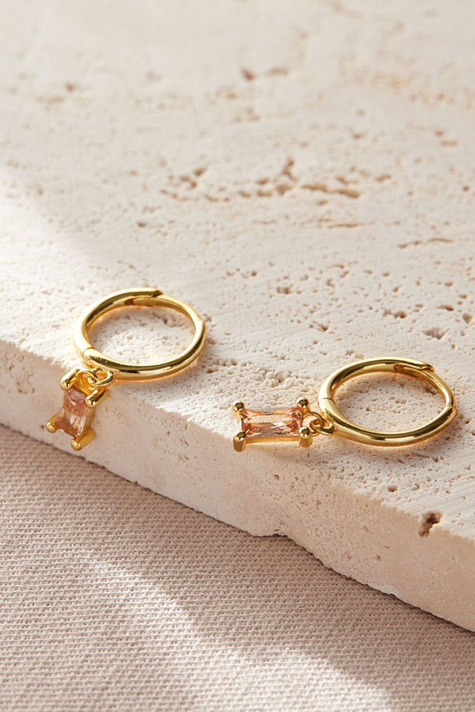 close up of the champagne pink cz gold dangle hoop earrings