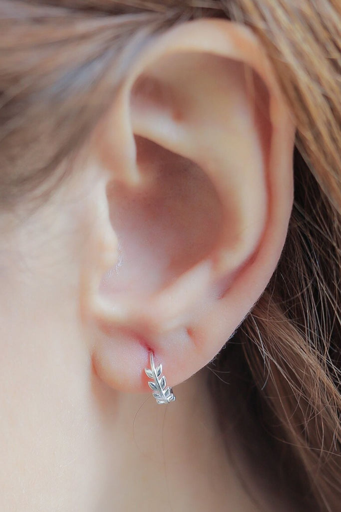 model wearing a silver olive huggie hoop earring in the earlobe showing the dainty size of the hoops