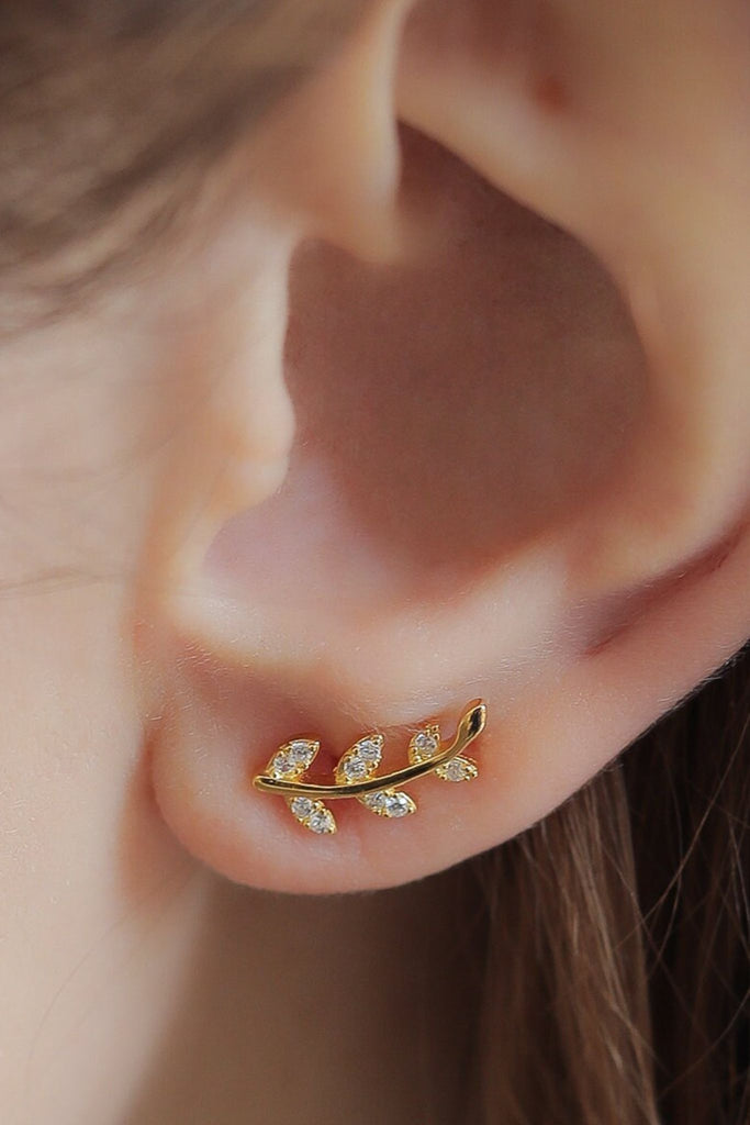 model wearing a gold leaf stud on the earlobe, showing the size of the earrings 