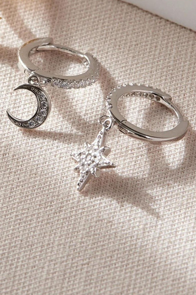 close up of the silver star and moon asymmetric dangle hoop earrings