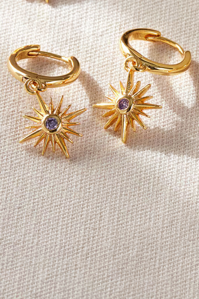 close up of the gold and purple cz crystal north star dangle hoop earrings