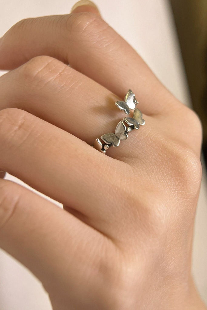 model wearing this adjustable butterfly ring on the middle finger