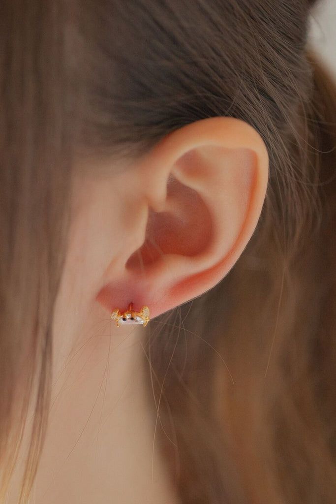 model wearing one of the crab studs on the earlobe, showing the dainty size of the earrings