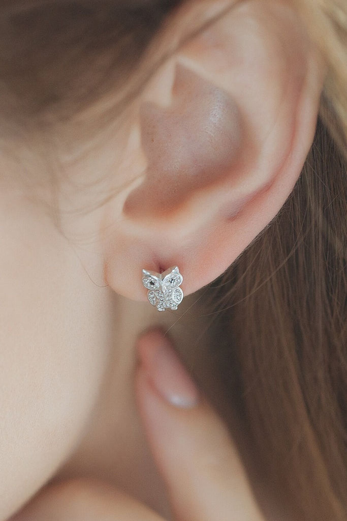 model wearing an owl stud on the earlobe, showing the size of the earrings