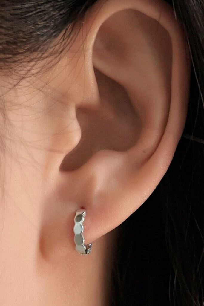 model wearing the silver honeycomb hoop earring, showing the geometric designs and snug fit of the earrings