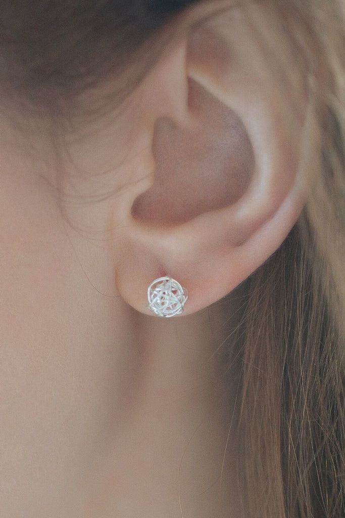 model wearing a sterling silver wire ball stud earring on the earlobe, showing the dainty size of the earrings