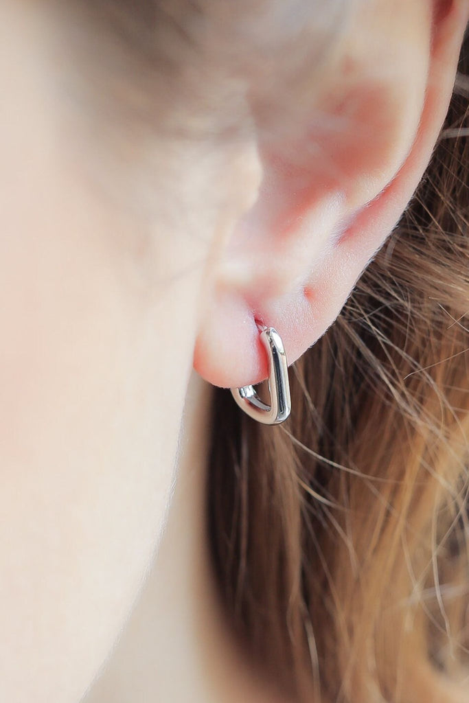 model wearing the u-shaped hoop on the earlobe, the earrings are small and hang just below the lobe, these are minimalist earrings