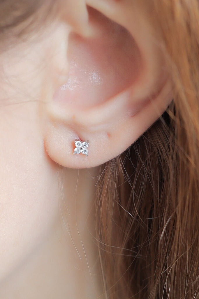 model wearing the silver sparkly clover stud earring on the earlobe, showing the dainty size of the earrings