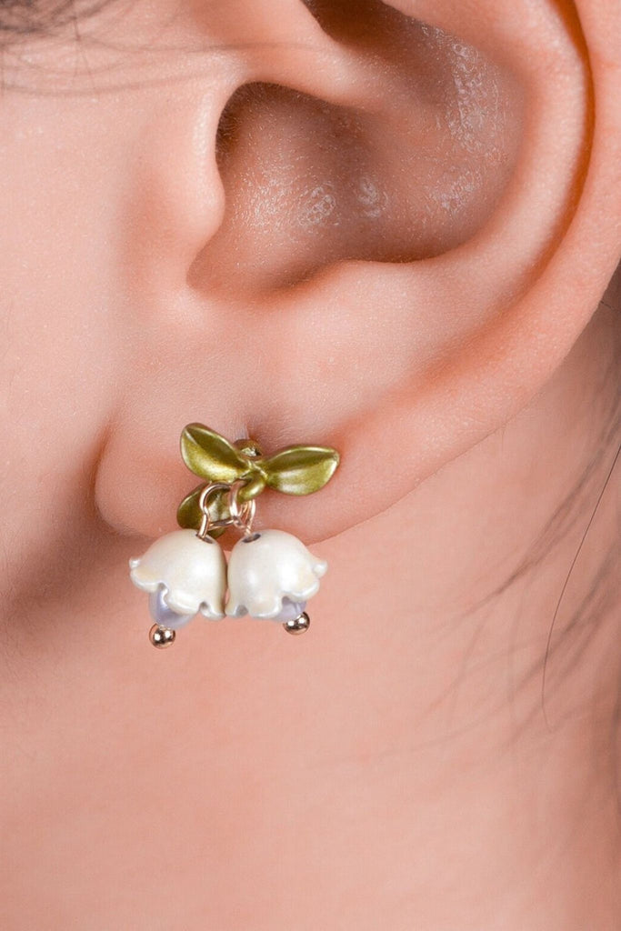 model wearing an ornate lily of the valley drop stud earring on the earlobe