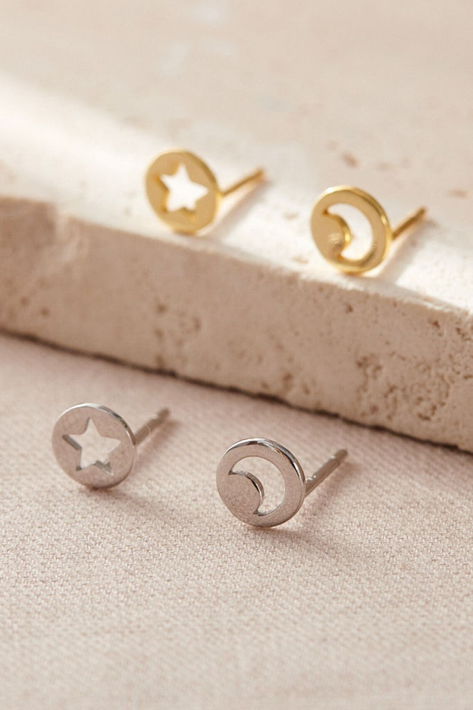 silver and gold small round stud earrings, in each pair one has a hollowed out star and one has a hollowed out crescent moon, the earrings have butterfly backs