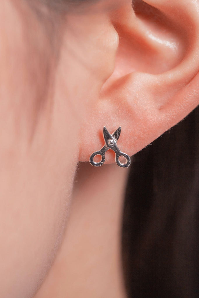 model wearing the small scissor stud earrings on the earlobe showing the dainty size of the earrings