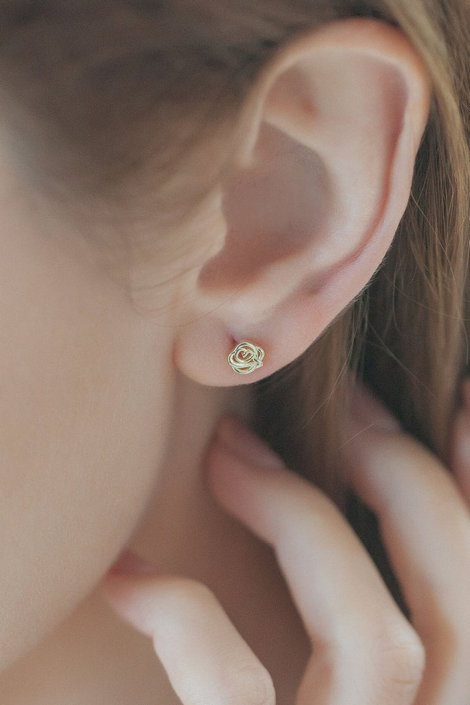 model wearing a small rose stud earring on the earlobe, showing the minimalist style of the earrings