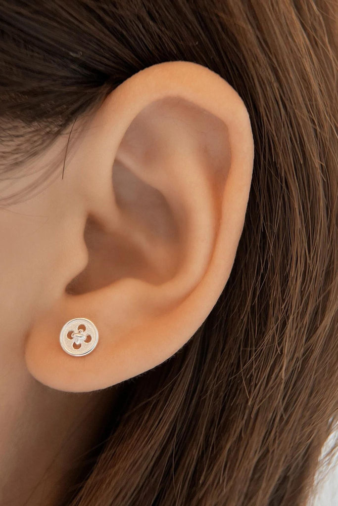 model wearing a silver button stud earring in the earlobe