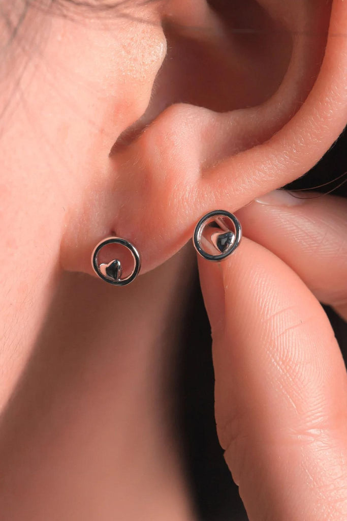 model wearing the silver circle heart stud earrings, showing the dainty size of the jewellery