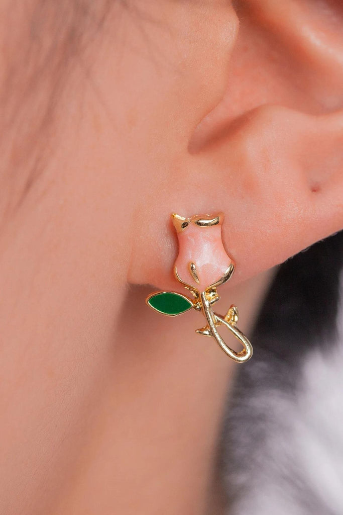 model wearing a pink tulip flower stud earring on the earlobe, the stem and leaf portion of the earring hangs below the earlobe