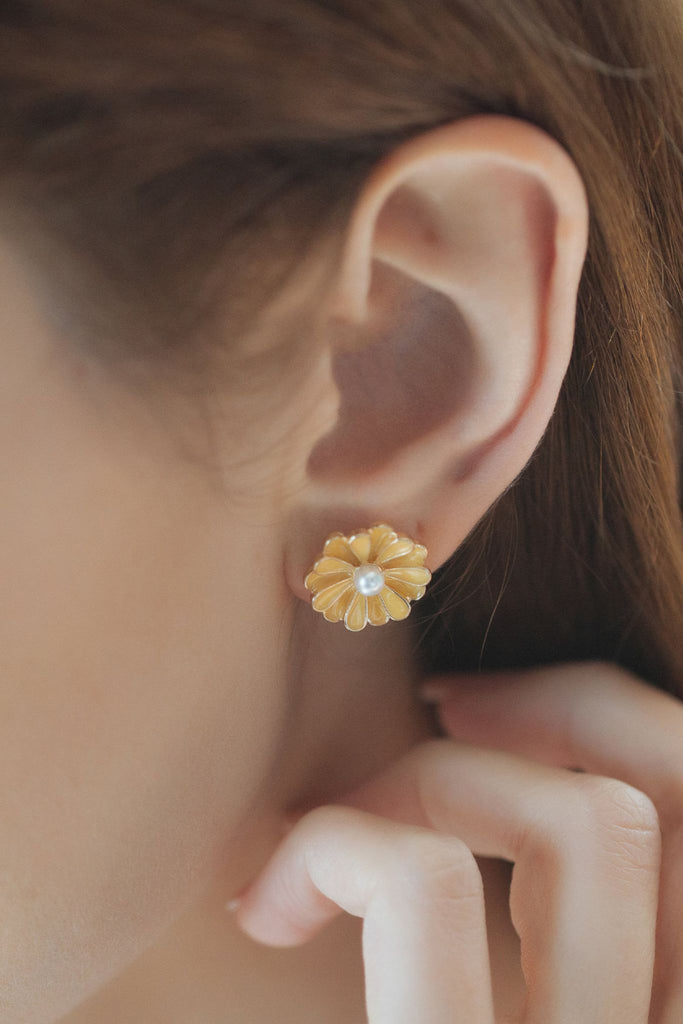 model wearing a large yellow flower stud earring, the earrings covers most of the earlobe