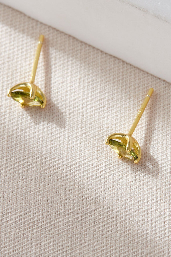 close up image of the gold plated silver olive green stud earrings, showing the oval shape of the studs