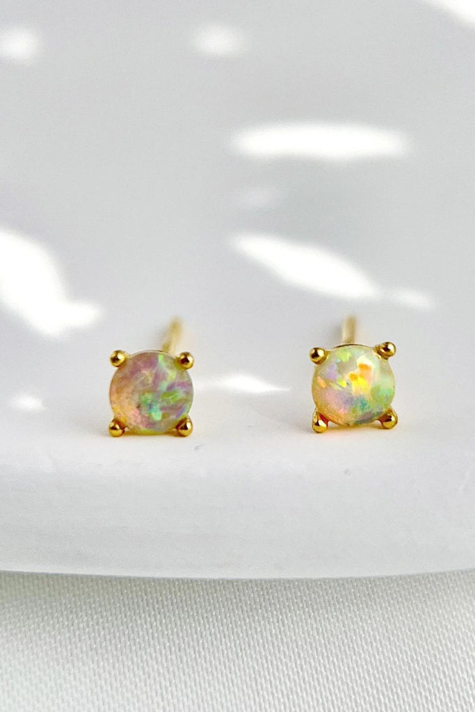 close up of the white opal stud earrings, the opal stones have a greenish hue in the light and are mounted on gold plates sterling silver earrings
