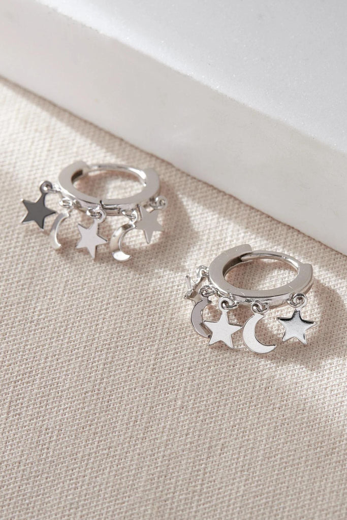 close up of the silver star and moon charm hoop earrings