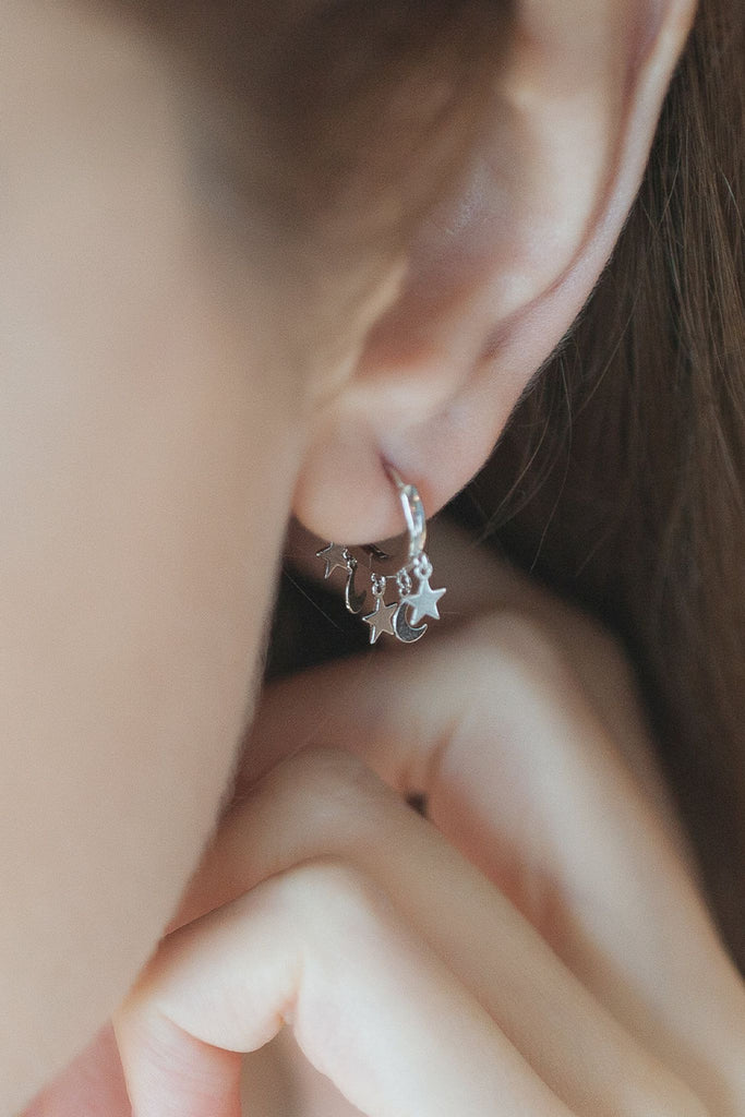 model wearing the silver star and moon charm hoop earring, showing the hoop with the stars and moons hanging just below the earlobe