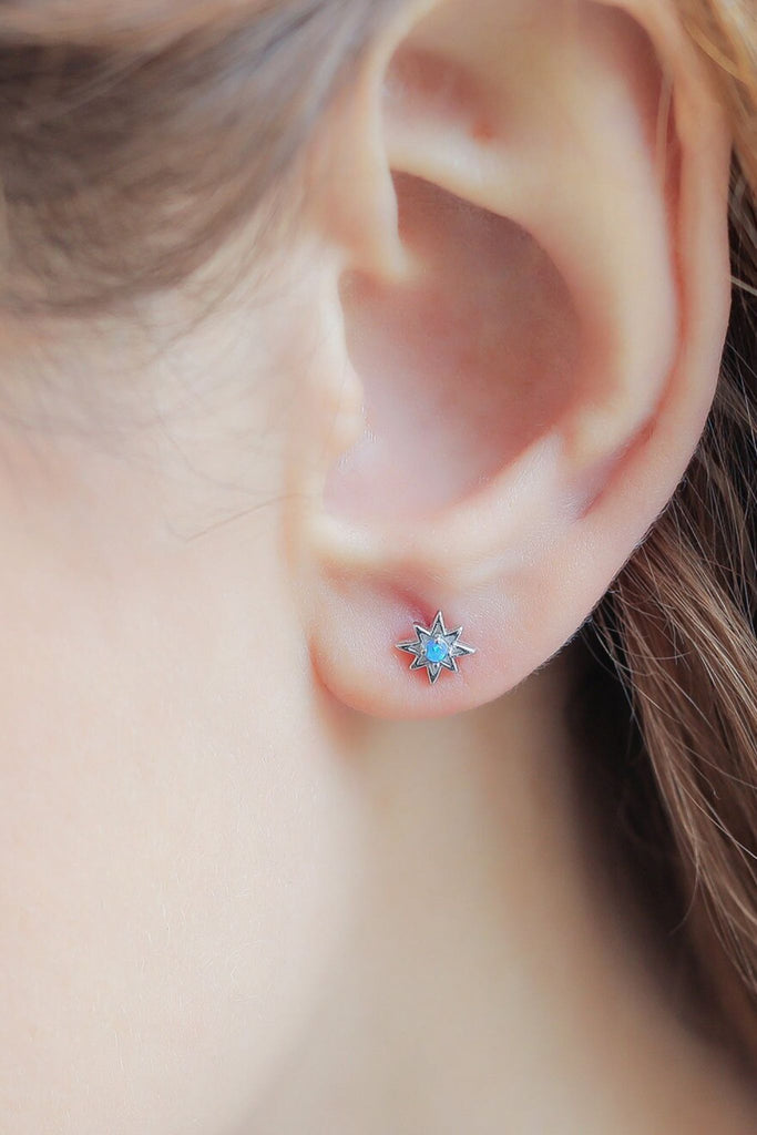 model wearing the silver and blue opal star stud earring on the earlobe, showing the dainty size of the earrings