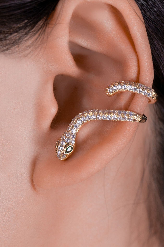 model wearing the gold coloured sparkly snake earring, the earring is secured in the earlobe and winds around the ear cuff