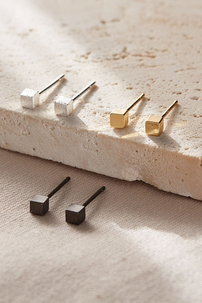 three pairs of square stud earrings, the studs are cube shaped and come  in silver, gold and black sterling silver