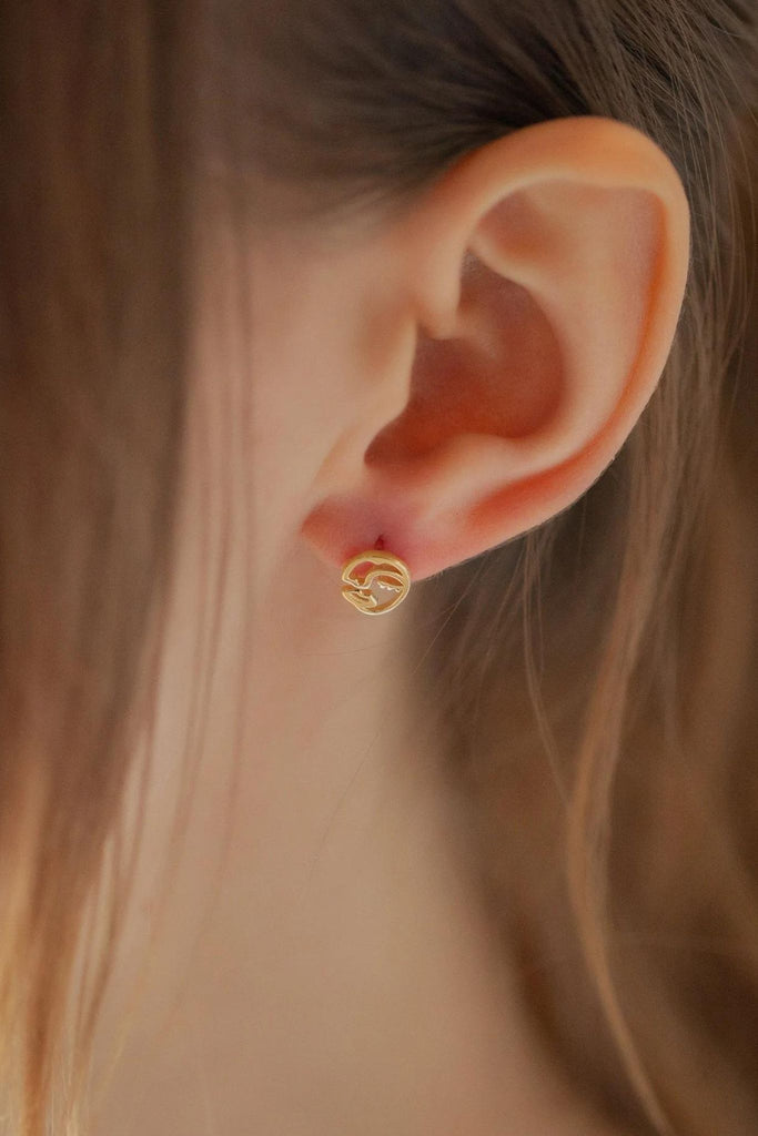 model wearing a gold face stud on the earlobe, showing the size of the earrings as small but hanging slightly off the edge of the earlobe