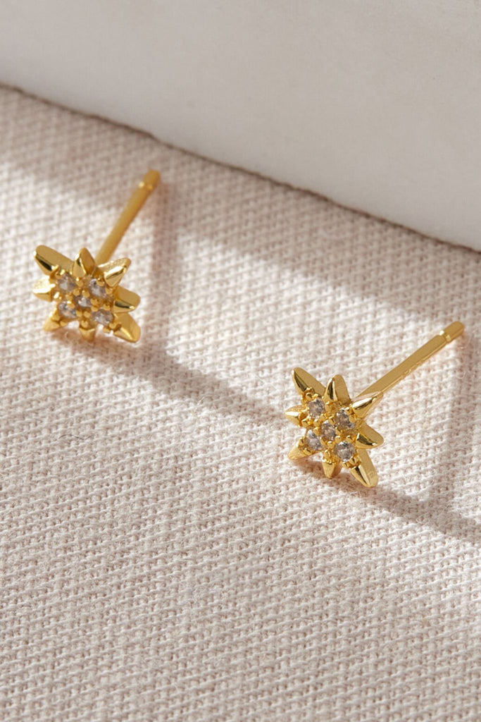 close up of the gold plated sterling silver and white cz sparkly eight point starburst stud earrings