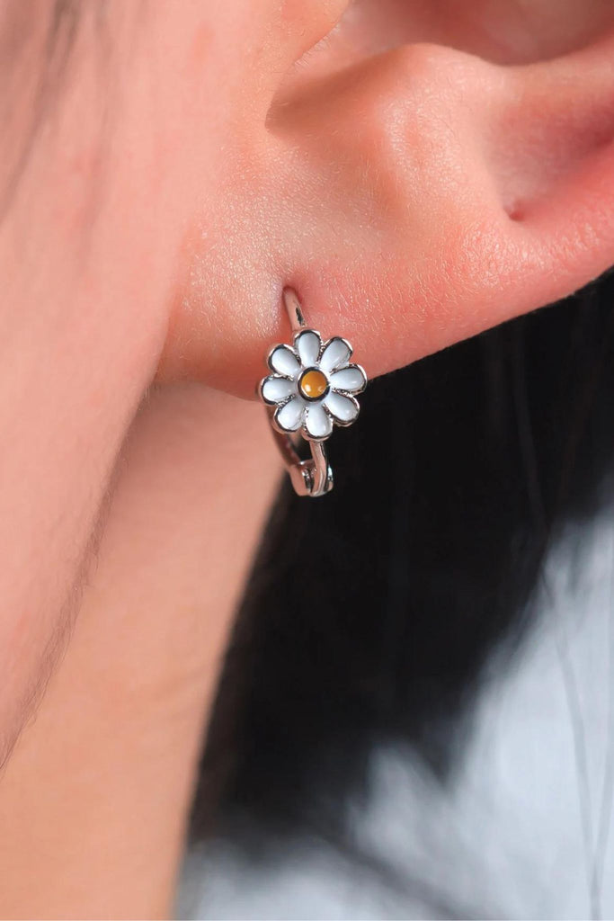 model wearing the silver daisy hoop earring, showing that the white and yellow daisy flower is prominent on the hoops