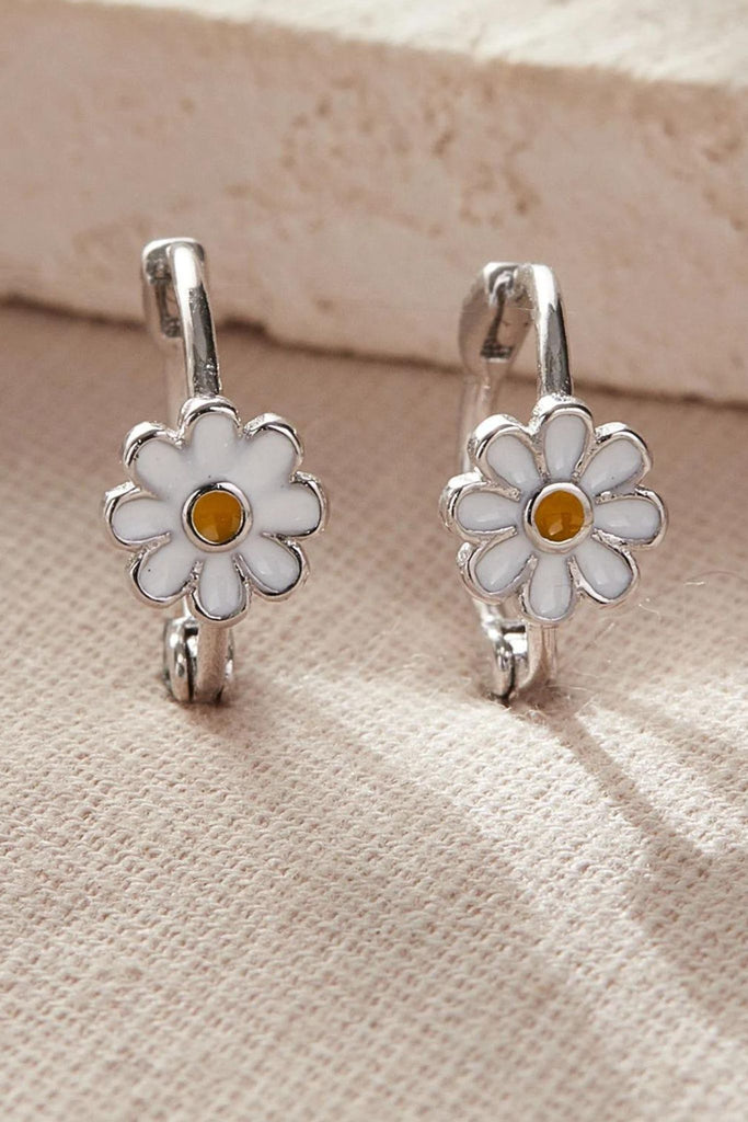 close up of the silver daisy hoop earrings, showing the white daisy flower with a yellow middle
