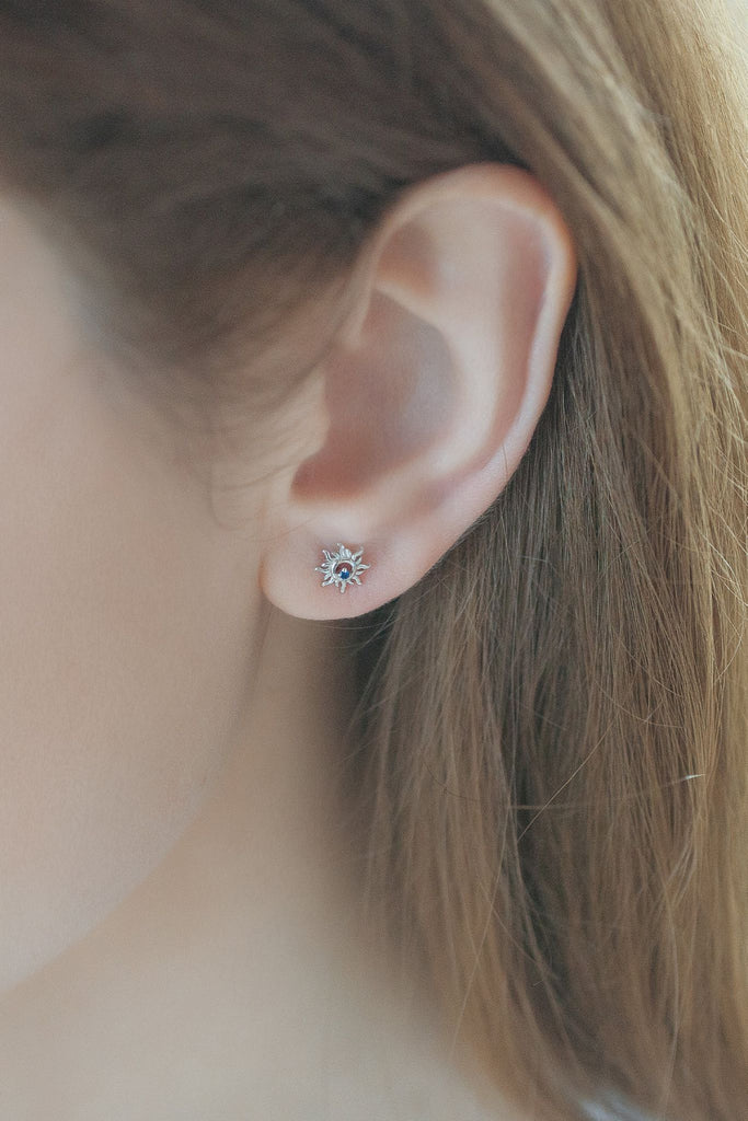 model wearing a silver sun stud earring on the earlobe showing the dainty size of the earrings