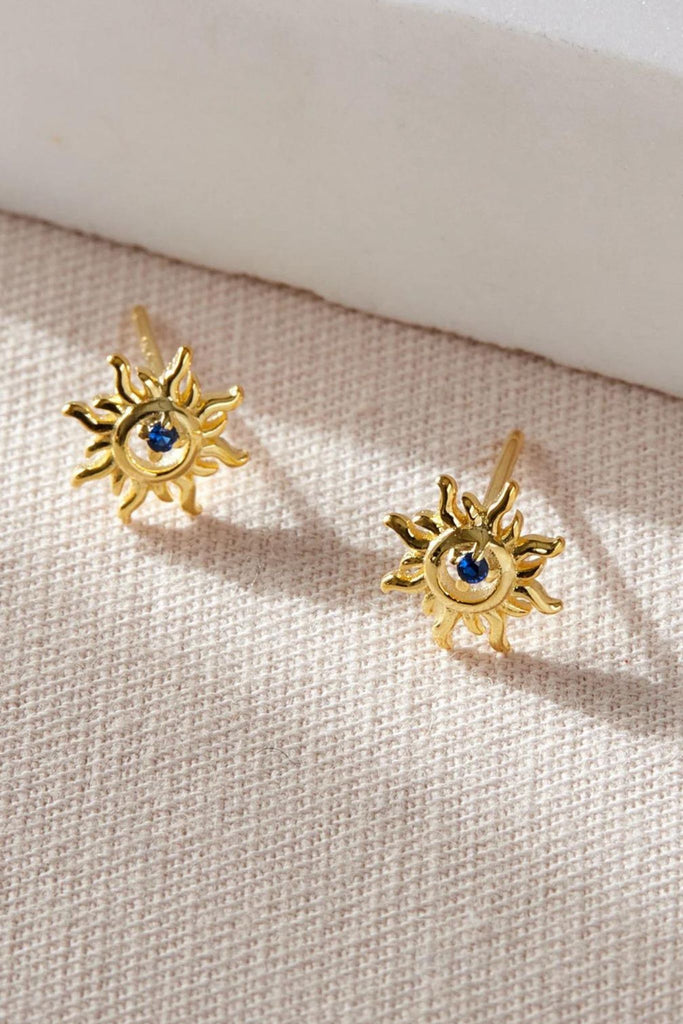 close up of the gold solar stud earrings, showing the blue cz crystal in detail