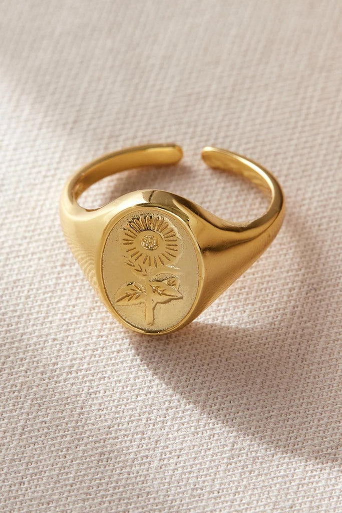 close up of the gold floral signet ring, showing the sunflower detail and the open adjustable band