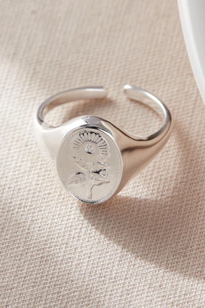close up of the silver floral signet ring, showing the sunflower detail and the open adjustable band