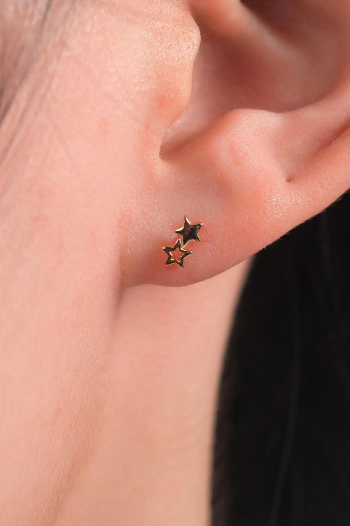 model wearing the gold double star stud earrings on the earlobe showing the dainty size of the jewellery