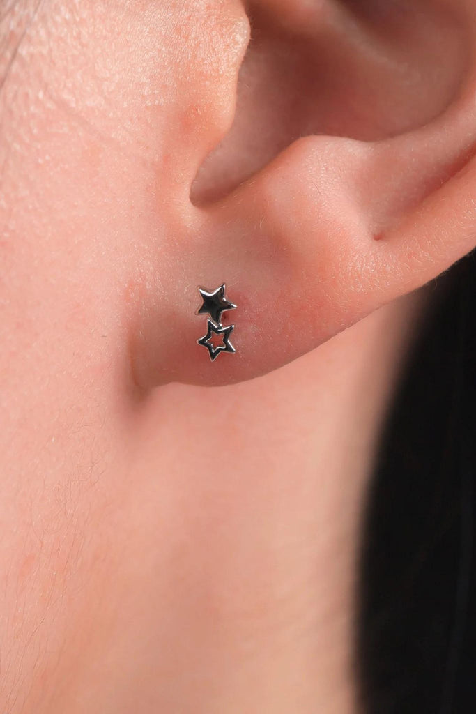 model wearing the silver double star stud earrings on the earlobe showing the dainty size of the jewellery