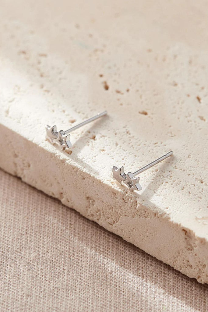 close up of the silver double star stud earrings, showing the one hollow star adjoined to one solid star per earring