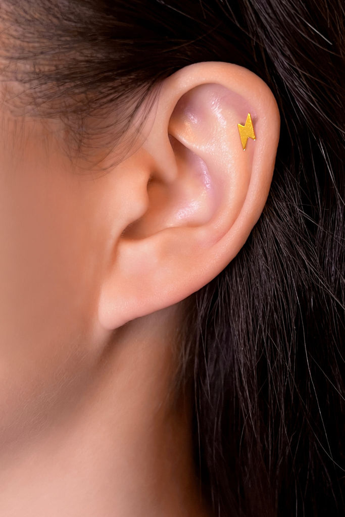 model wearing a gold coloured lightning bolt cartilage stud on the ear cuff