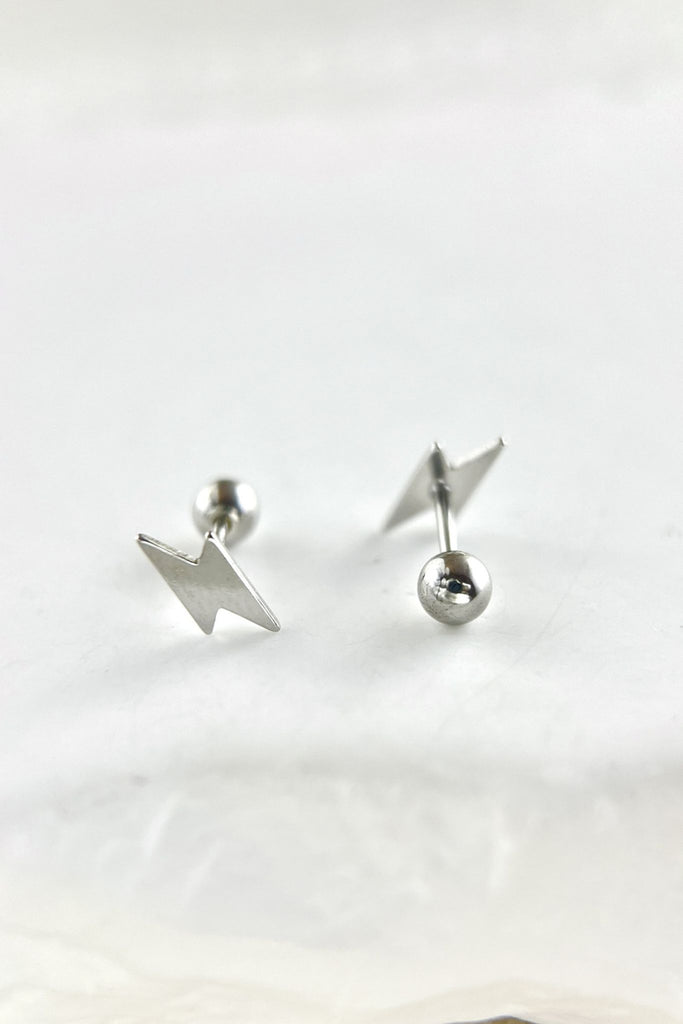 close up of the silver coloured sterling silver lightning bolt cartilage stud earrings, showing the ball back fastenings