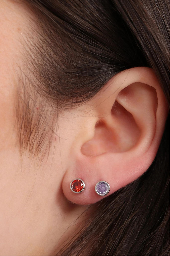 model wearing two of the round studs on the earlobe, showing the size of the birthstone earrings