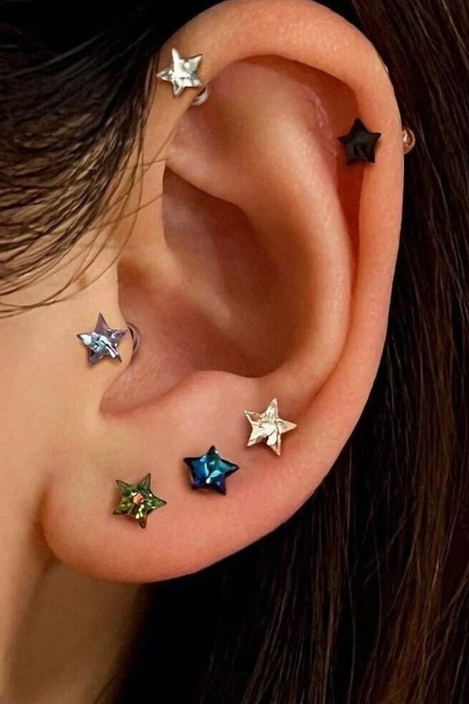 model wearing several colours of these cz star stud earrings showing that they can be worn in a variety of piercing locations